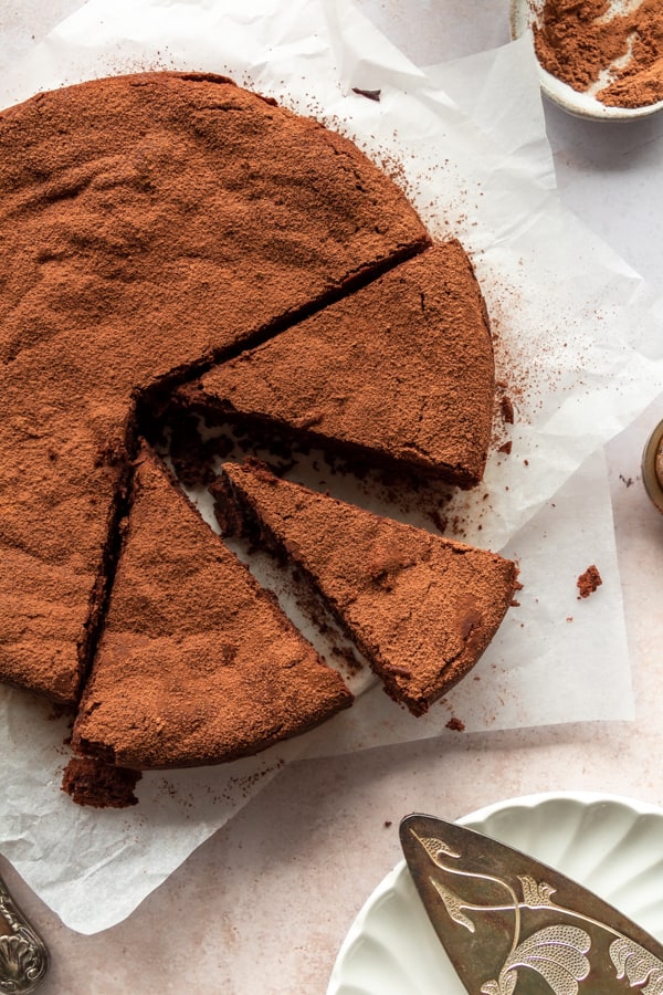triangle slices of Flourless Chocolate Cake on baking paper with cocoa powder 