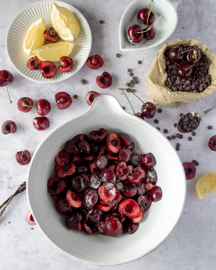 Halved cherries with sugar, lemon juice and vanilla seeds on a bowl. 