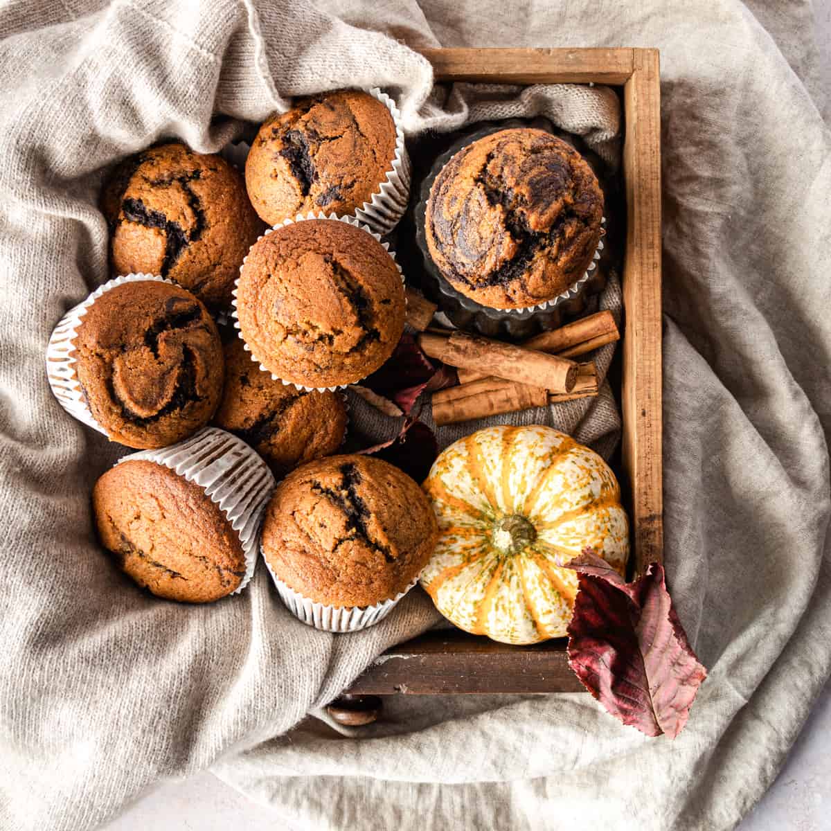 Muffins with a pumpkin on a wood box with grey wool. 