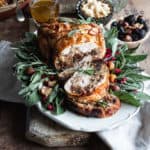 Stuffed chicken roast recipe on a serving plate with herbs