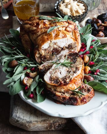 Stuffed chicken roast recipe on a serving plate with herbs