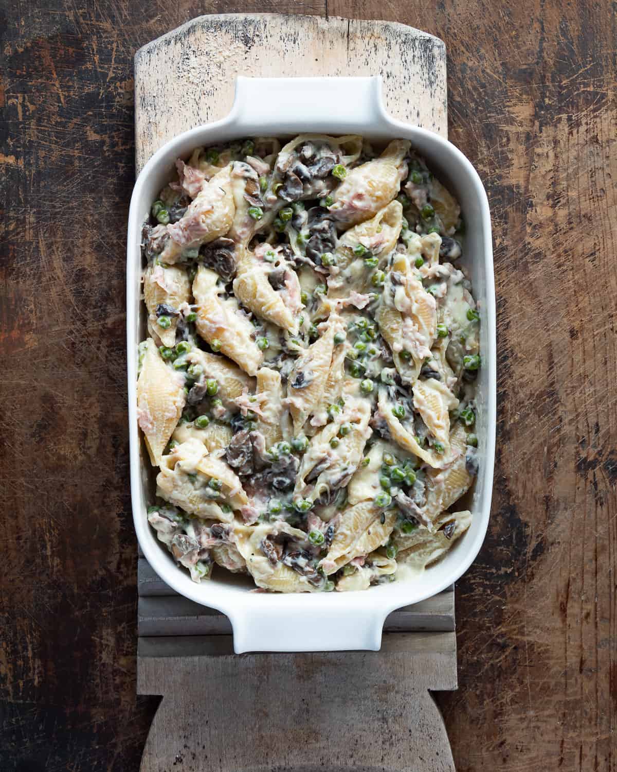 Assembled pasta with peas, mushrooms, bechamel sauce , cheese and ham in a casserole.