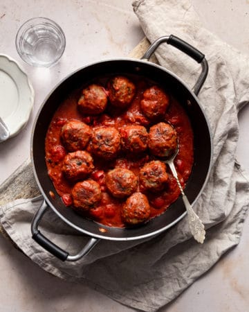 Meatball in a frying pan with a spoon inside.