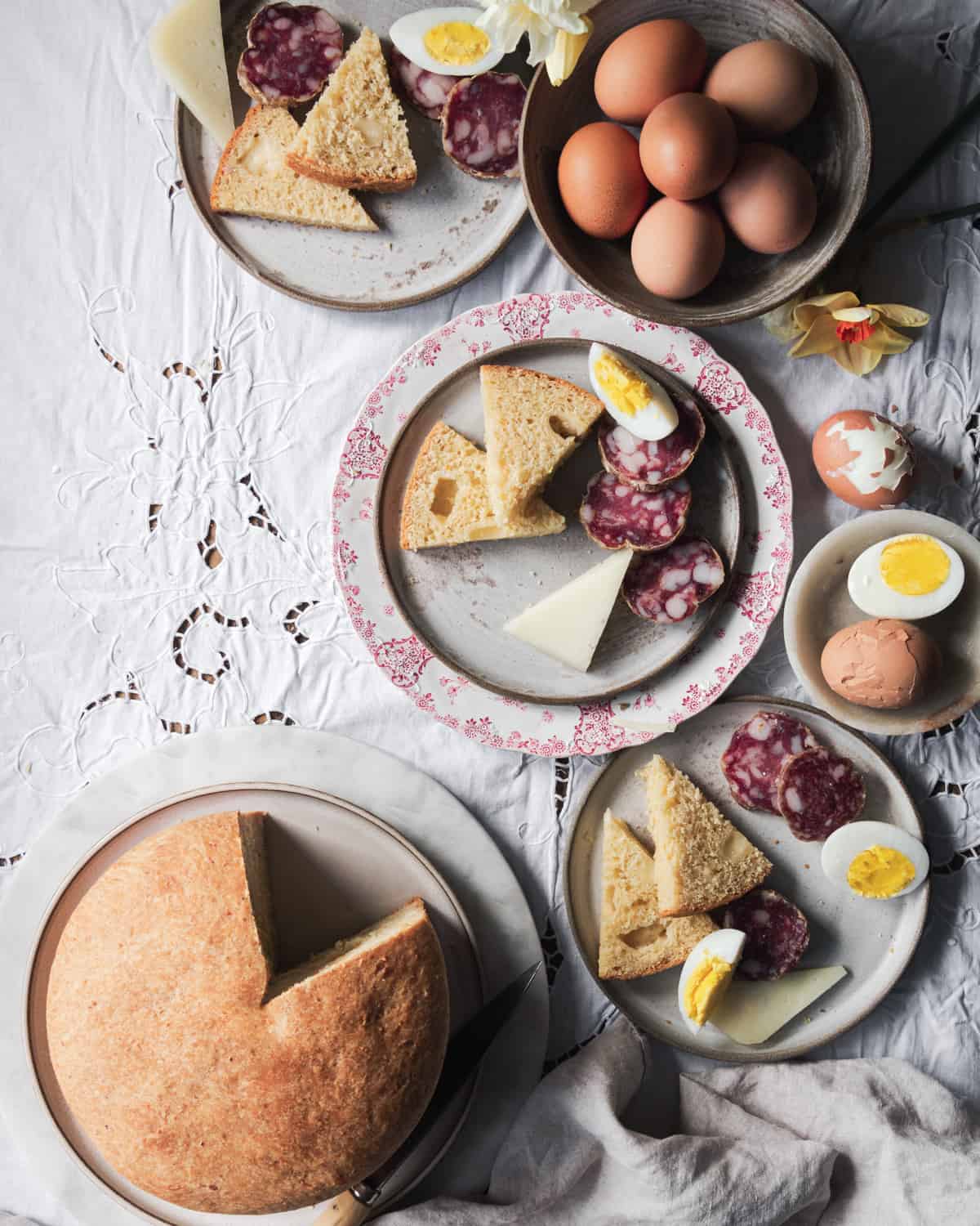 Italian easter cheese bread sliced in plates with salami. cheese and boiled eggs. 