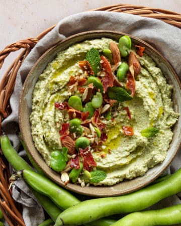 Broad beans pesto in a bowl placed in a wooden basket
