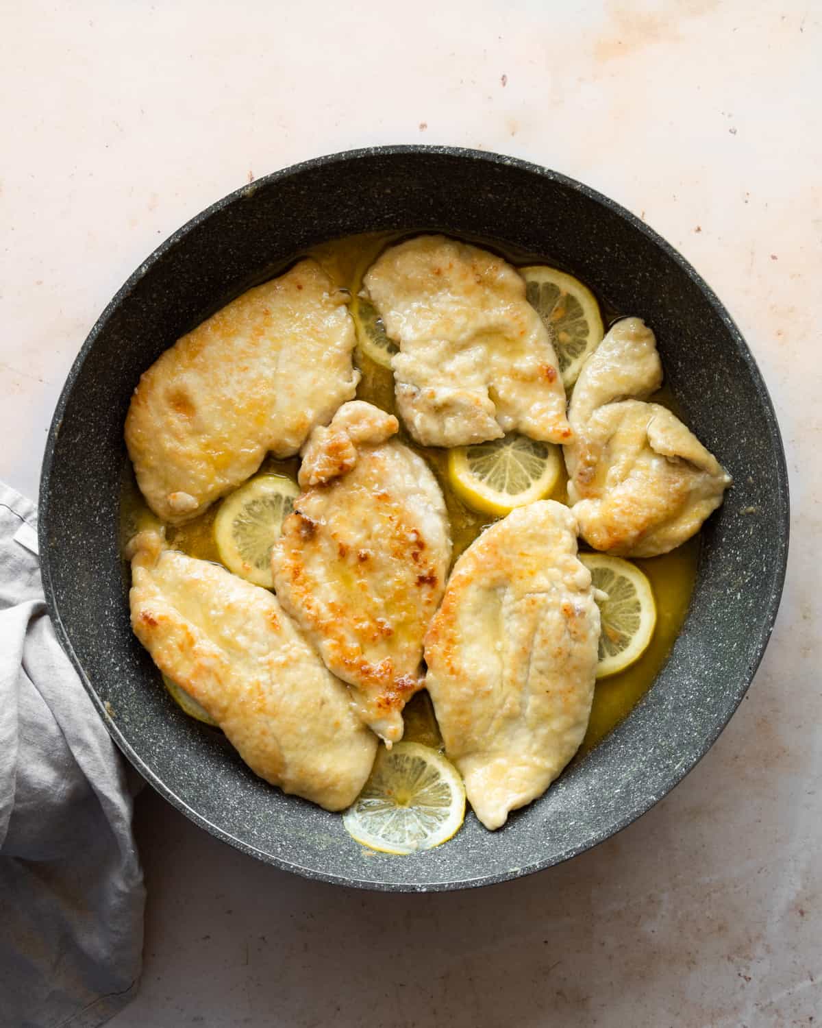 Ready chicken breast in a frying pan with lemon slices. 