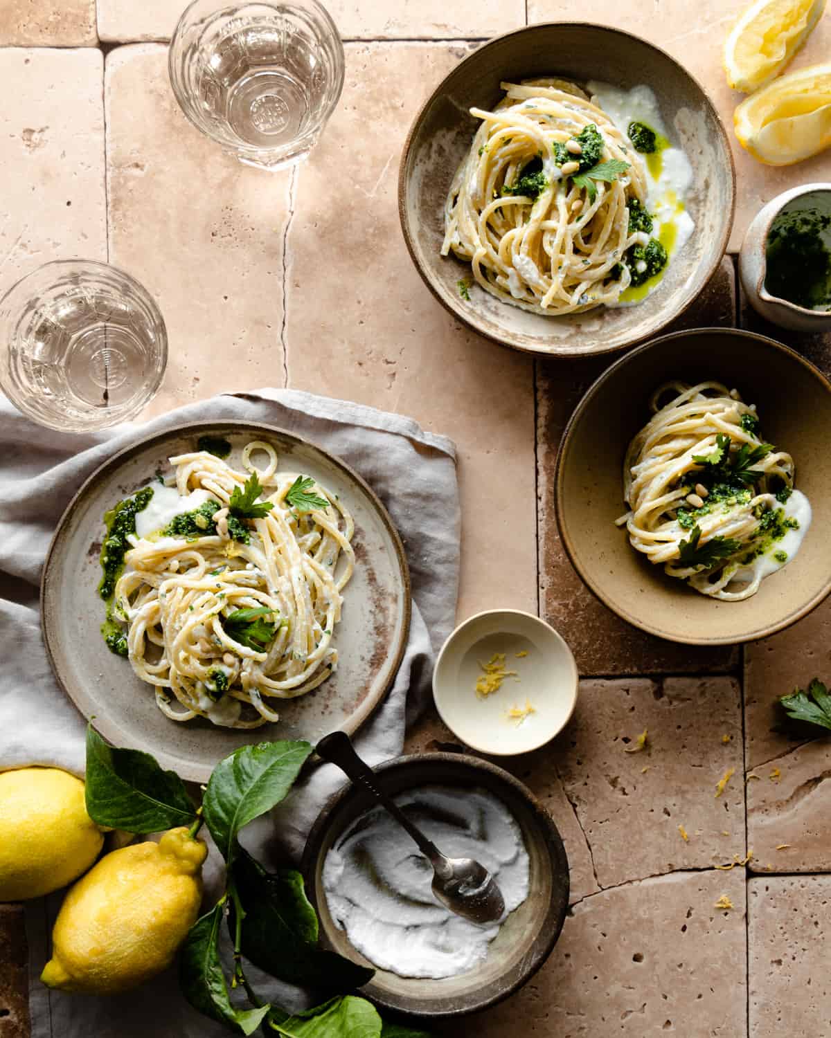 Pasta with ricotta and lemon on differents bowls with lemons around and parsley pesto.