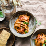 Pink pasta sauce recipe on a bowl with some basil leafs on top.