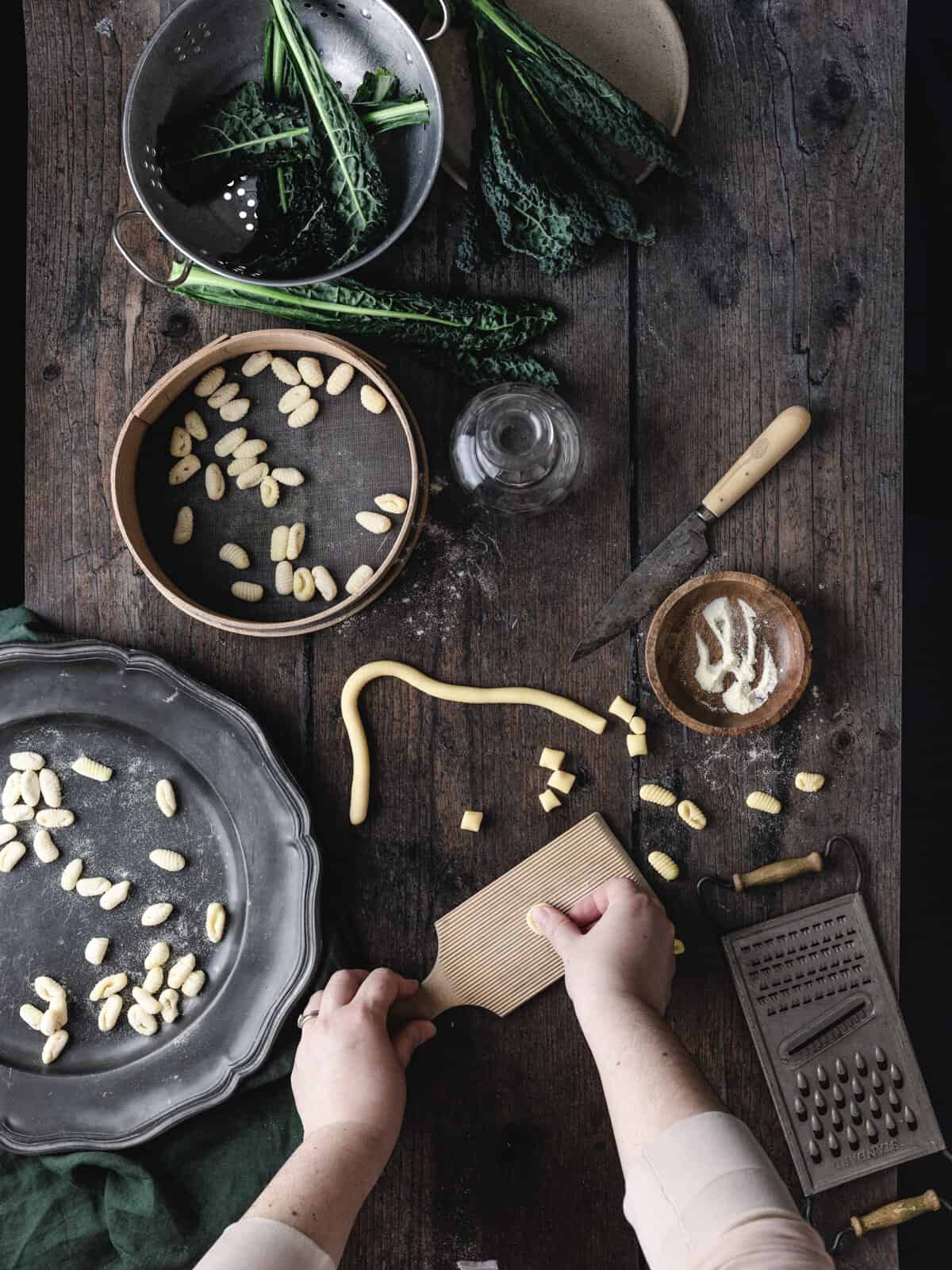 An overhead shot of hand showing how to roll the gnocchetti sardi on a gnocchi board