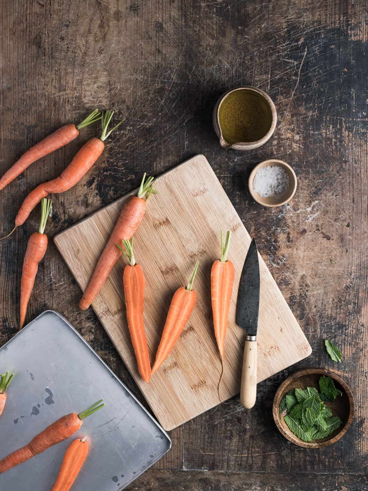 Overhead shot showing how to cut the carrots in halves on a chopping board.