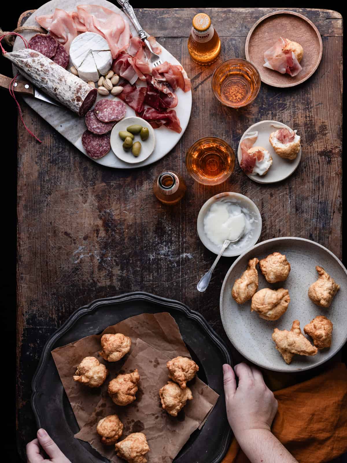 Fried coccoli on serving plate served on a table along with cheese and cured meats.