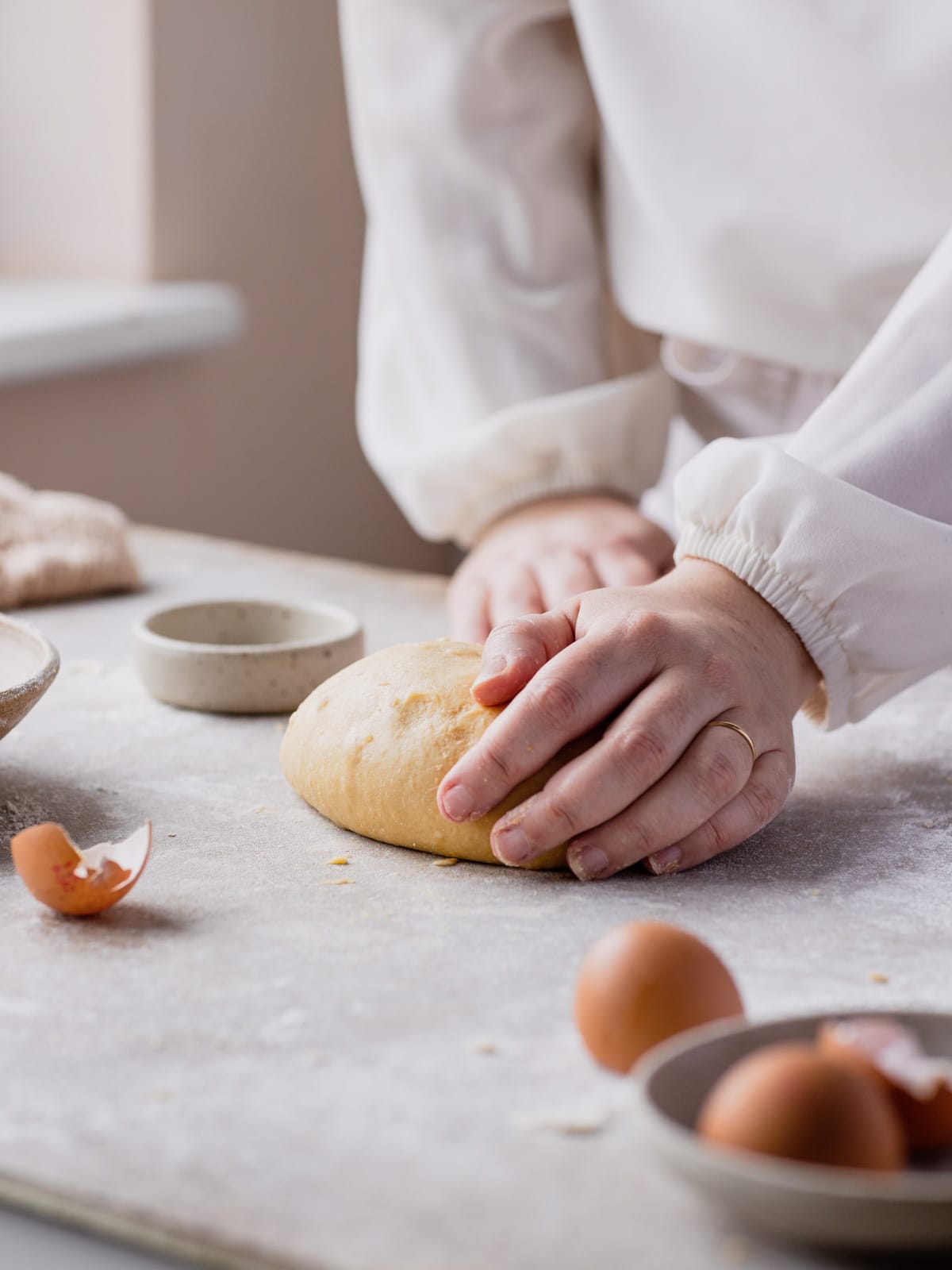 Hand kneading the pasta dough on a backdrop with egg shells around