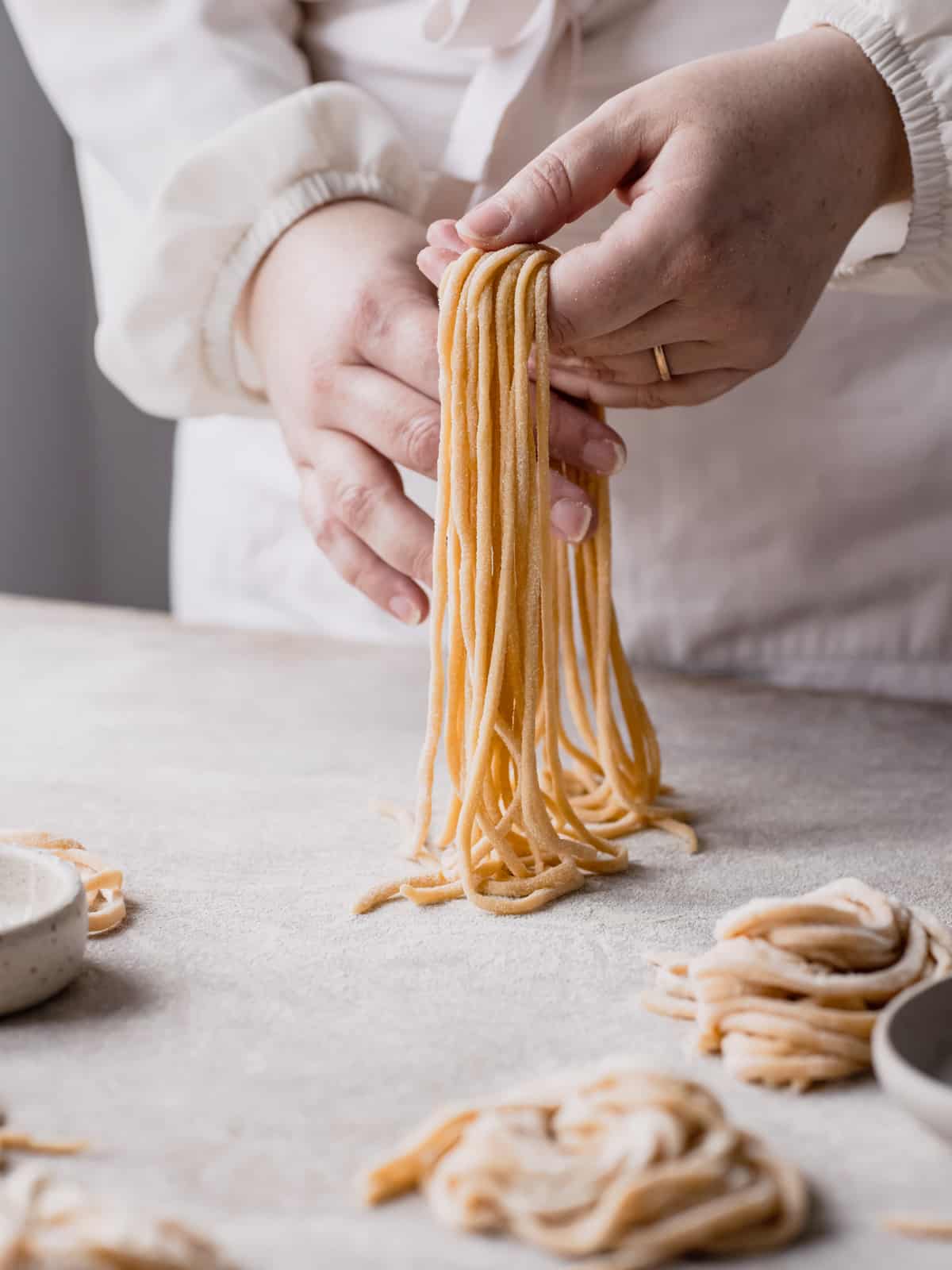 Hands holding the Tonnarelli with around some pasta nests