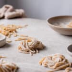 Close up of Tonnarelli pasta nest on a backdrop with flour on top