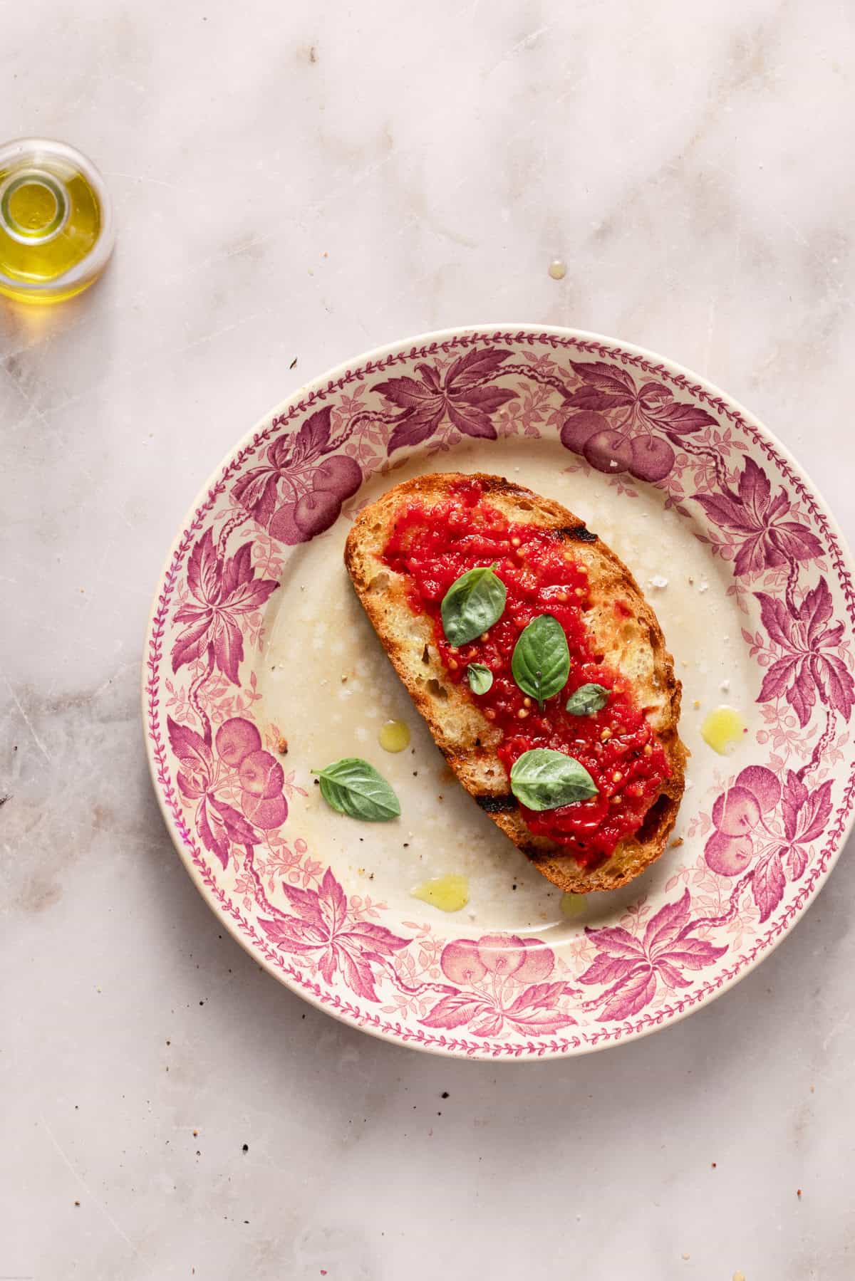 A slice of bread with the juicy spread on a pink plate on a marble table.