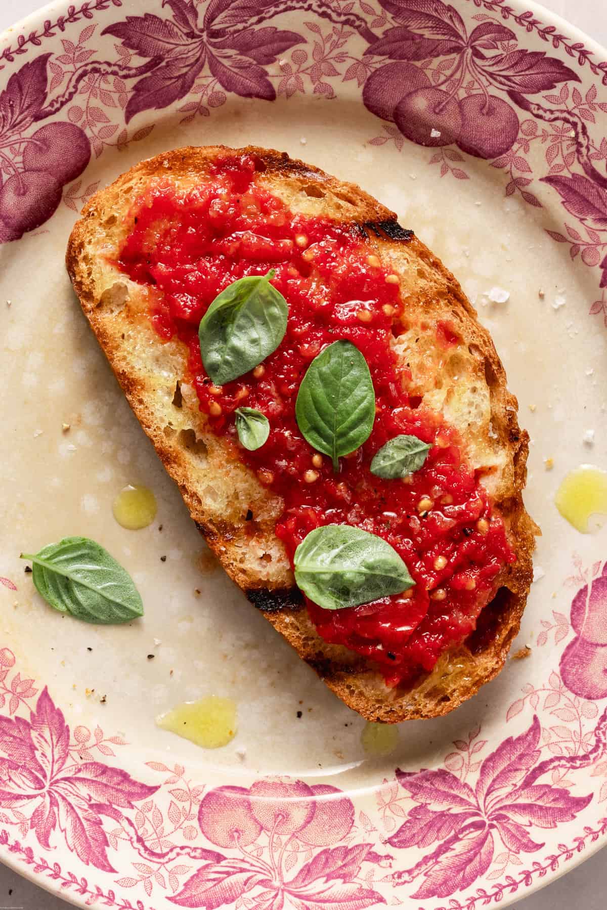 A close up of a slice of pane e pomodoro on a pink plate.