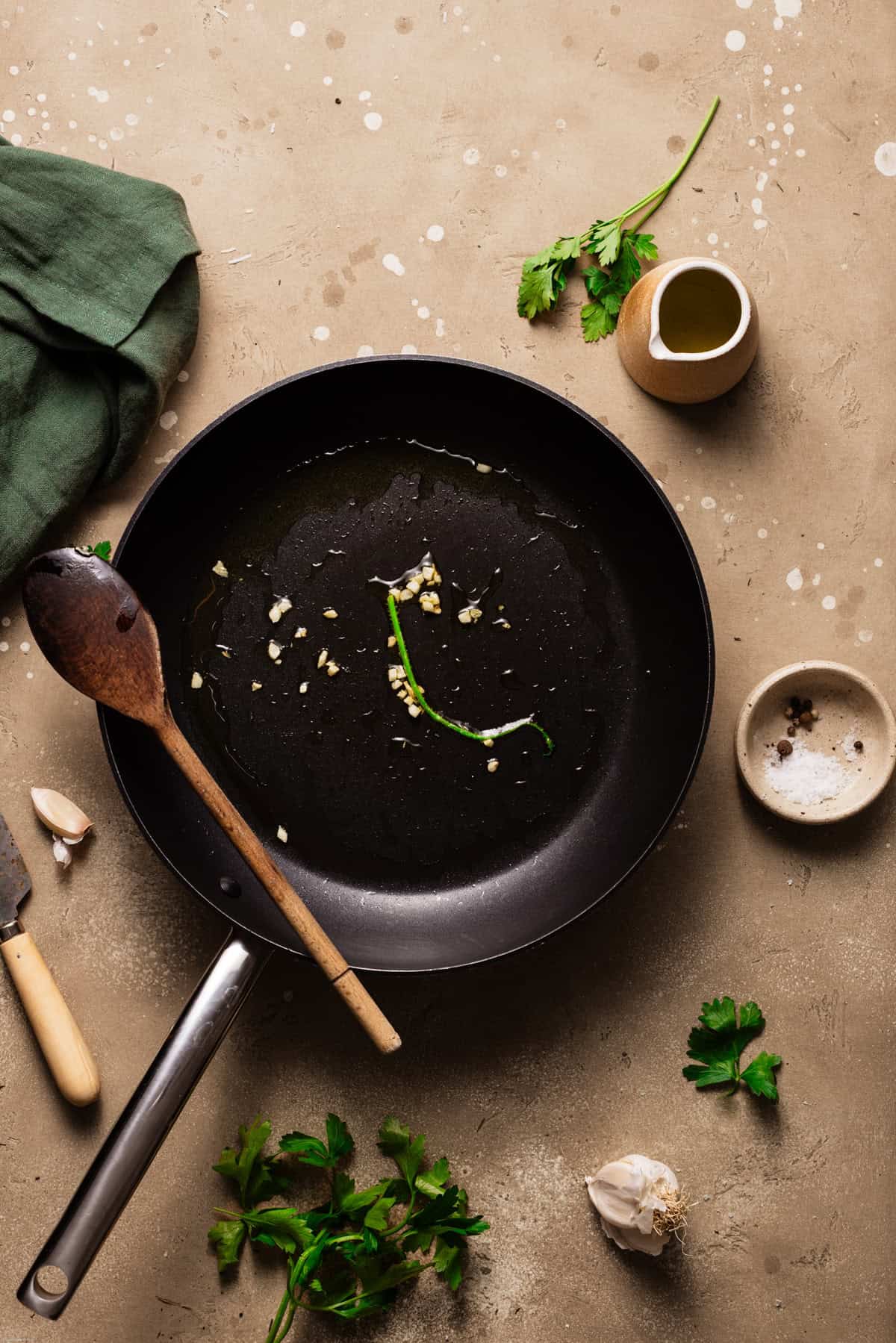 A step shot showing the pan with the sautéed garlic and parsley in it.