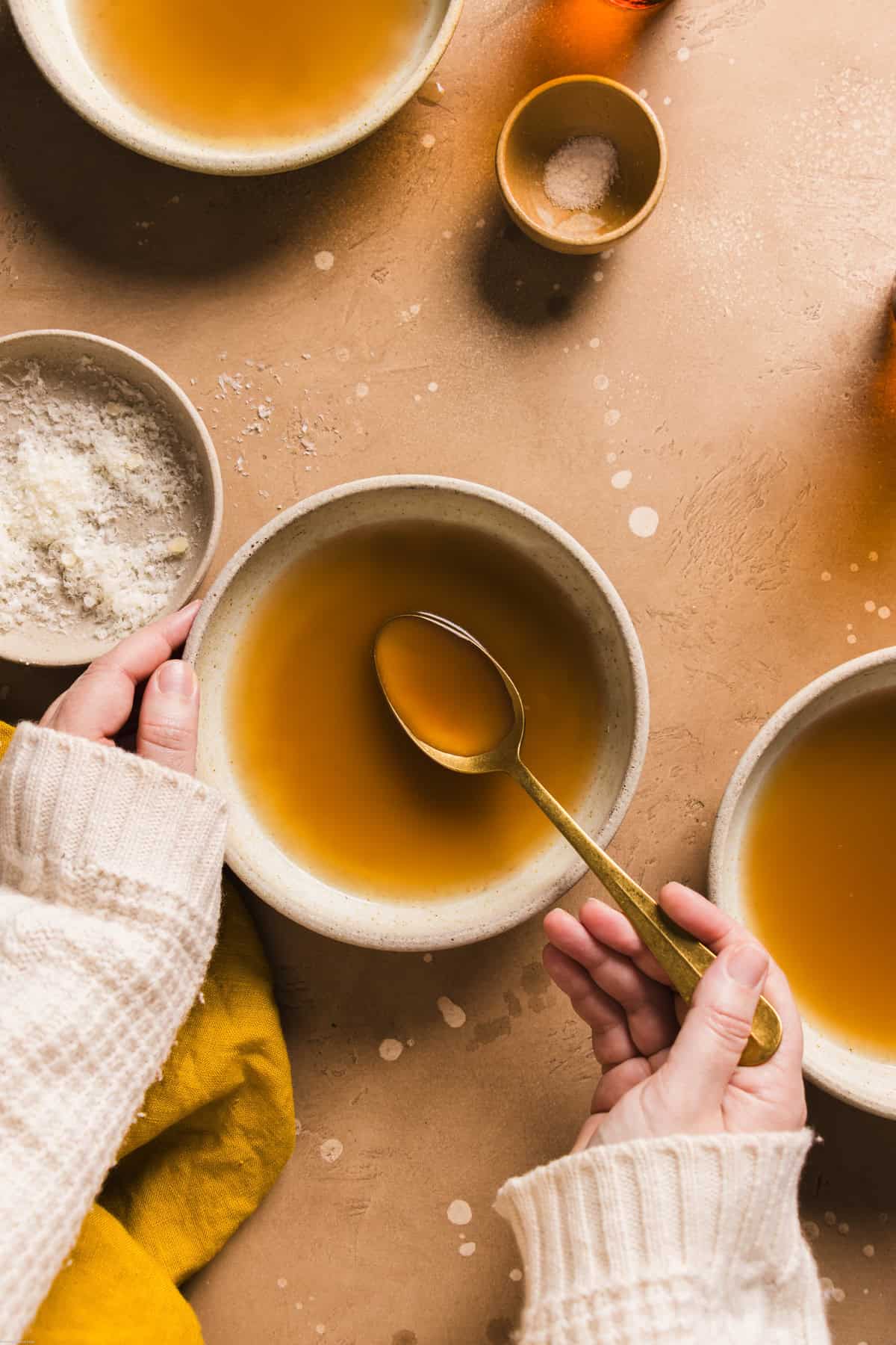 an authentic Italian broth recipe photo showing a woman holding the spoon with the beef broth on it