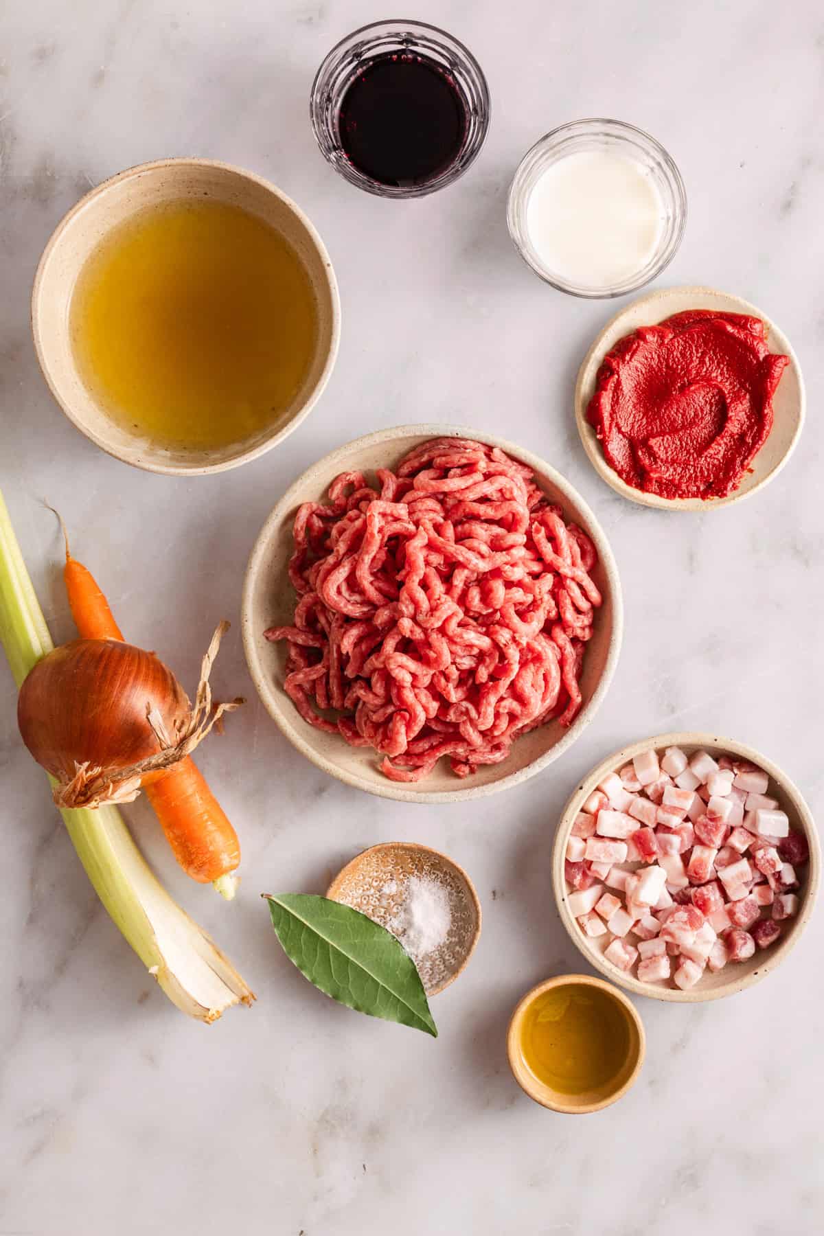 ingredients to make tagliatelle al ragu on a marble countertop