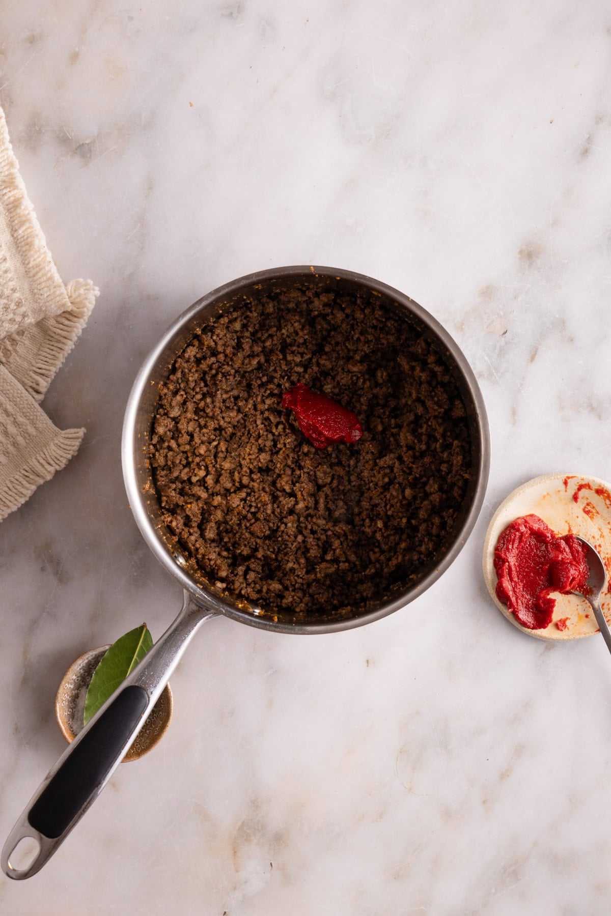 A large pot showing the brown meat with some tomatoes paste on top'
