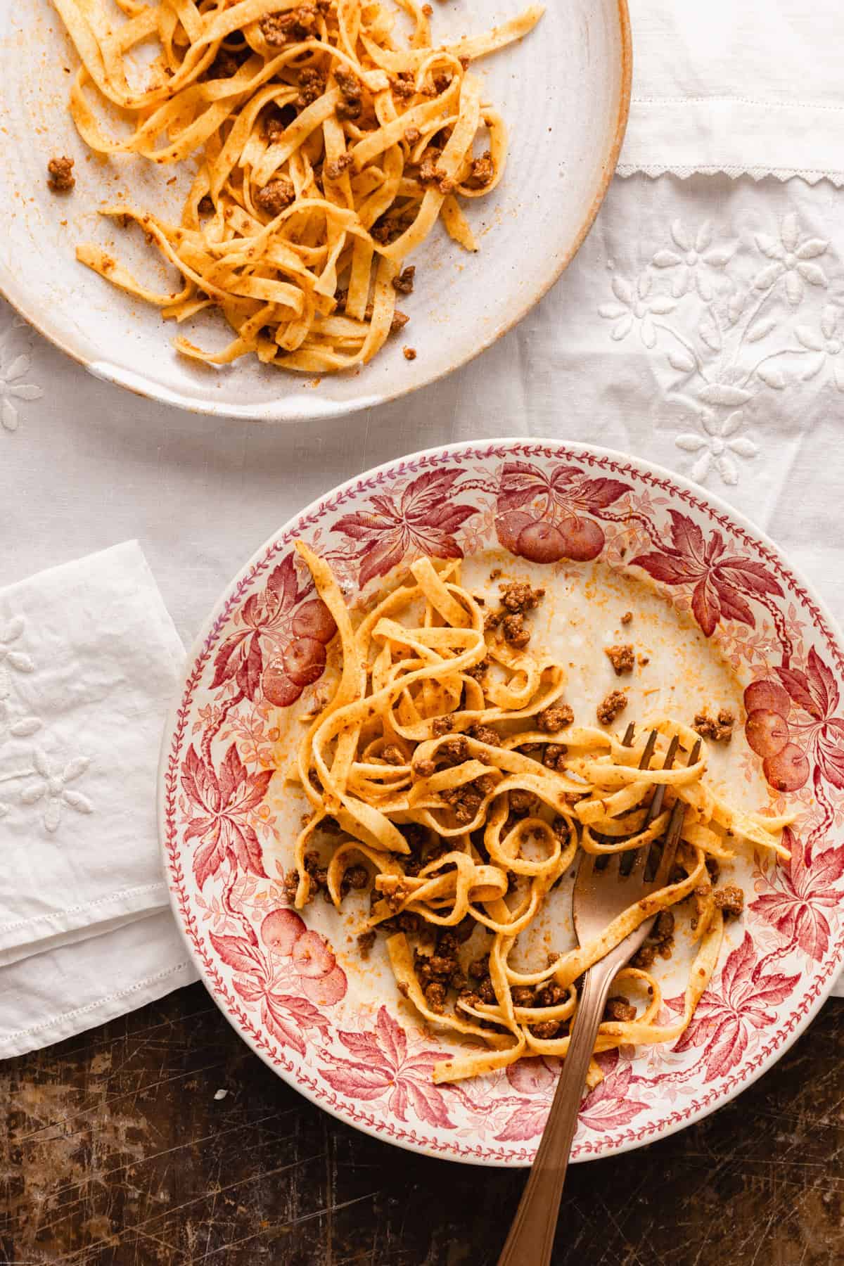two different plates showing the tagliatelle al ragu been eaten with a fork