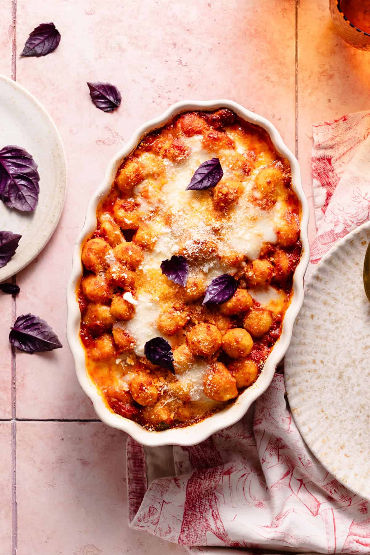 baked gnocchi al forno on a red baking dish on top of a pink background