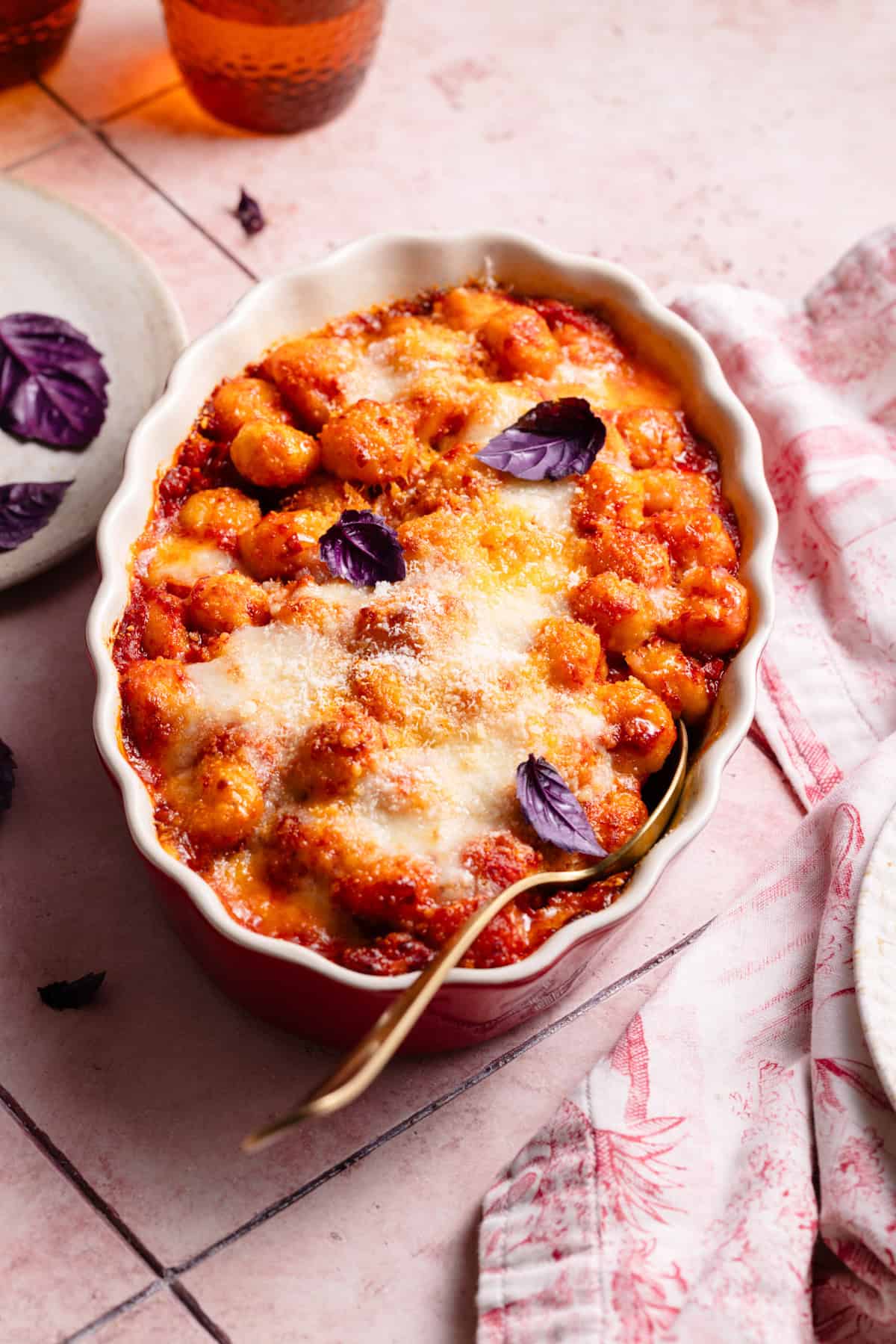 baked gnocchi al forno on a red baking dish with a golden spoon inside