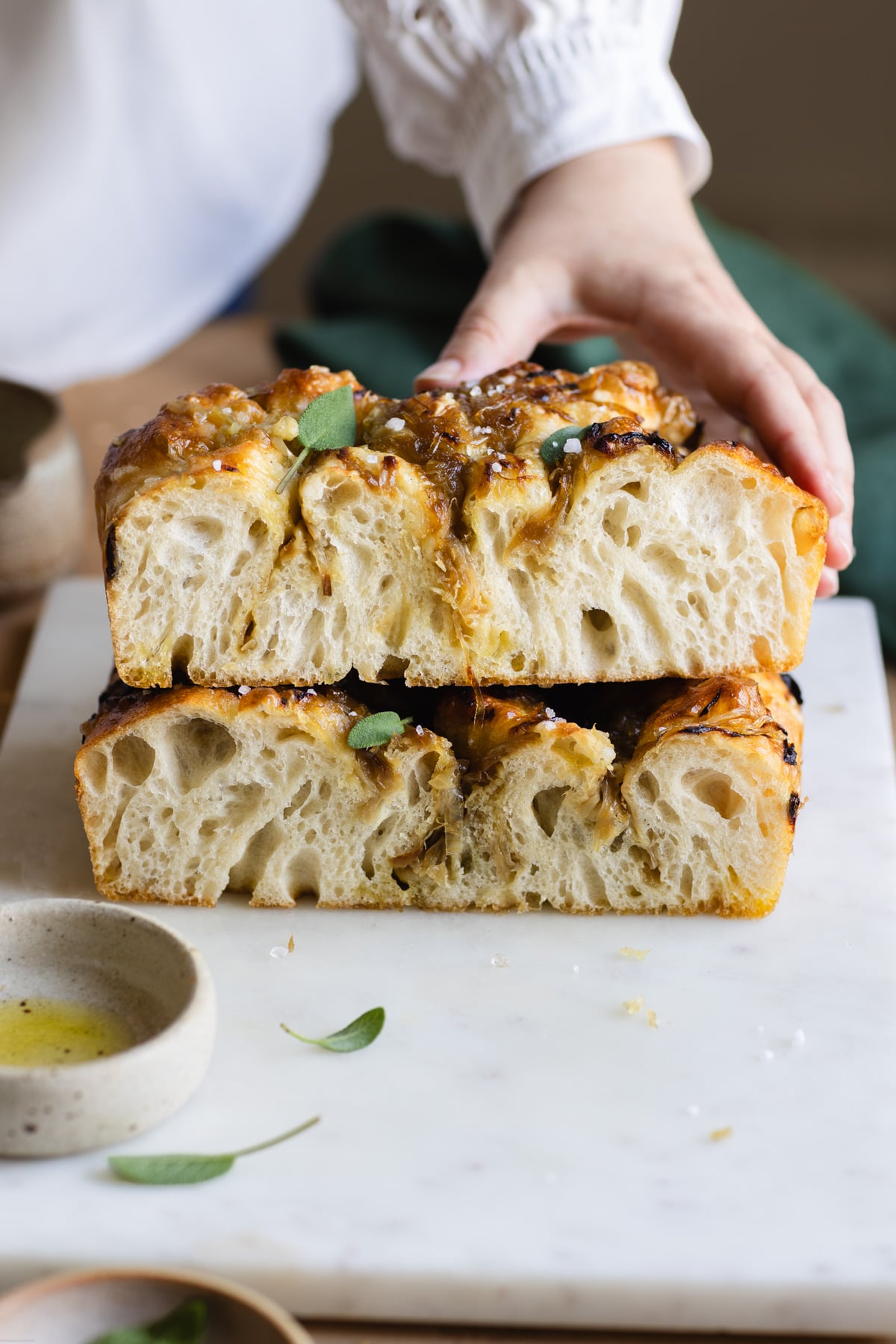 hand reaching slices of caramelized onion focaccia placed on top of each other