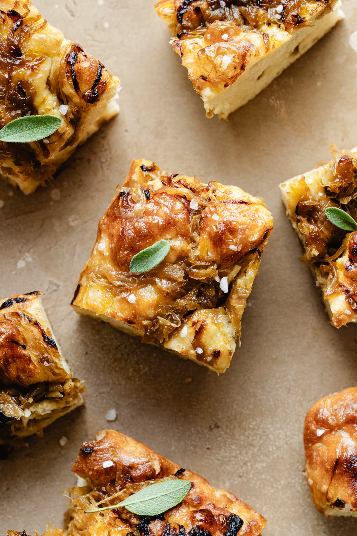 slices of focaccia with caramelized onion on a brown backdrop