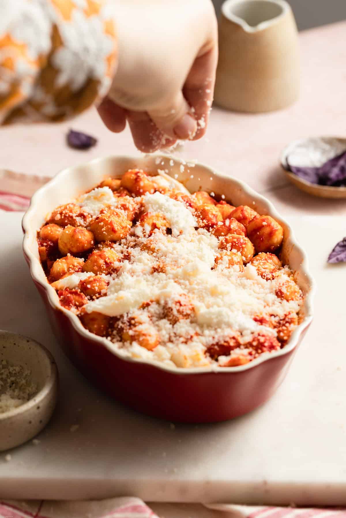 hand sprinkling some parmigiano reggiano on top of gnocchi
